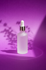 Wall Mural - Transparent frosted glass dropper bottle with silver lid with serum or essential oil. Purple background with daylight and beautiful shadows.Skincare products, natural cosmetic. Beauty concept for face