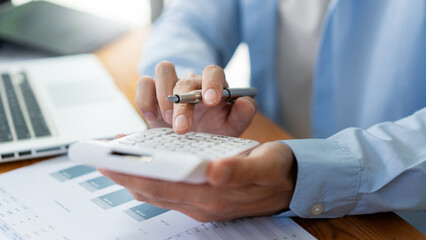 Wall Mural - Business analyst concept the accountant looking at the information on the computer screen while calculating the numbers