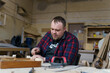 © NADIN - carpenter in a plaid shirt working with wood in the workshop
