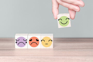 Aufkleber - Hand holding a wooden cube block with happy smile face icon, good feedback rating customer review, customer service evaluation concept.