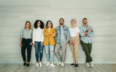 Group of creative businesspeople standing against a wall