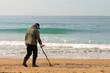 A man with a metal detector and a shovel on the seashore. A treasure hunter with a metal detector. A man is looking for a treasure.