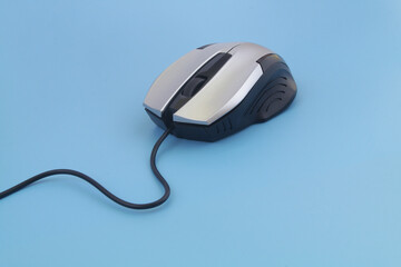 Silver computer mouse with cord on blue background