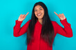 Cheerful young latin woman wearing red shirt over blue background demonstrating hairdo