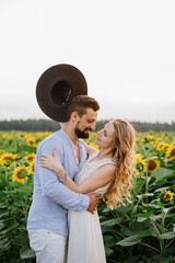 Couple walks in the sunflowers in a field on a summer day