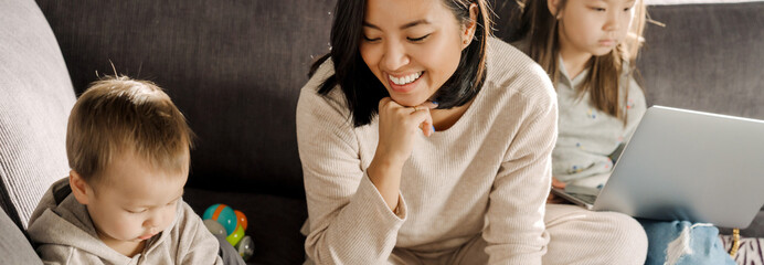 Wall Mural - Young asian woman smiling while spending time with her children