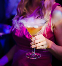 Woman Holding A Smoky Cocktail At A Nightclub.