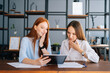 © dikushin - Portrait of two shocked young business women working using digital tablet at meeting desk with job documents at office. Business female colleagues using touchscreen computer for project discussion