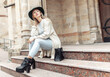 © splitov27 - Young fashion woman in trendy stylish clothes sits on steps in urban architecture. Lifestyle, street fashion