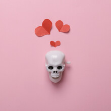 Skeleton Skull With Hearts On A Pink Background. Valentine's Day Or Halloween Celebration Concept. Minmal Layout