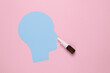 Paper-cut human head with nasal spray on a pink background. Runny nose treatment