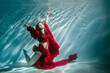 © Inna888stock - Attractive red-haired young woman swims beautifully underwater in a red dress