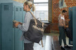 Two young women using their lockers in gym before workout side view shot