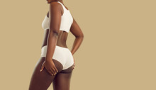 Attractive Plus Size Black Woman In Underwear. Hot Brown Skinned Model Wearing Comfy Natural Cotton Undies Holding Hands On Thighs Standing On Color Background. Female Body Concept, Rear Back View