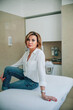 © sun_house_ann - confident adult woman sitting on a couch in the office of a cosmetologist doctor. the hostess of the cosmetology clinic sat down in the office of her cosmetologist