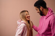 © Halfpoint - Fashion studio portrait of a happy young couple in hoodie posing over pink background.