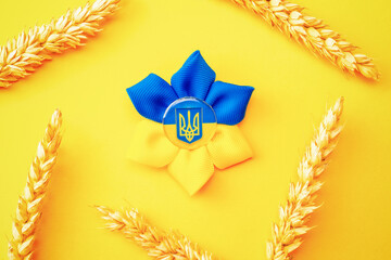 Ukraine flag symbol background. Ukrainian flower trident symbol with wheat grain ear isolated on yellow banner. Support Ukraine concept.