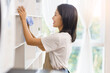 © Pichsakul - Home relaxation concept, Young woman use fabric to wipe clean and place the books in home showcase