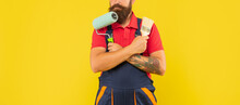 Cropped Man In Work Clothes Hold Paint Roller And Brush On Yellow Background