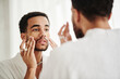 © AnnaStills - Young man applying transparent patches under his eyes while standing in bath opposite mirror