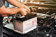 © BLKstudio - A auto mechanic carries a replacement car battery for car electrical maintenance