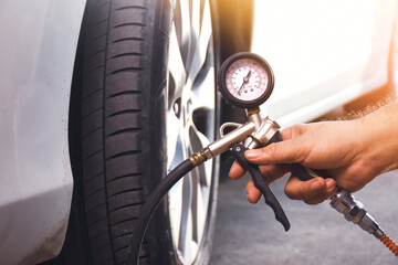 Wall Mural - A auto mechanic inflates a tire with an air tire inflating gun