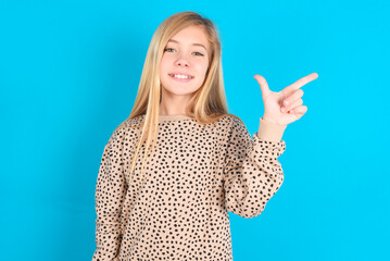 Wall Mural - little caucasian kid girl wearing animal print sweater over blue background  pointing up with fingers number eight in Chinese sign language BÄ.