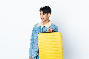 Poster - Chinese man over isolated background in vacation with travel suitcase