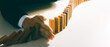 © Thapana_Studio - Risk management, business man hand Stop the continuous falling of wooden dominoes, stop the impact of the business crisis. hedging Solving business problems for success.