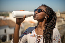 Young Woman With Sunglasses Drinking Water From A Reusable Bottle In A Sunny Day