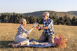© pucko_ns - Couple mature woman and man sitting on blanket and make a picnic at the middle of the field in nature