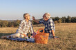 © pucko_ns - Couple mature woman and man sitting on blanket and make a picnic at the middle of the field in nature