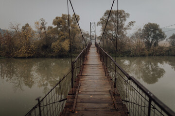 Eerie scenery of a wooden suspension bridge over the river in a cloudy day