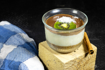 homemade vanilla and chocolate with butter cookies and nuts pudding decorated with kiwi fruit and coconut with cinnamon sticks