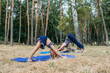 © irissca - Family fitness and yoga. Happy mom exercising with baby girls on grassy land against trees in forest. Young woman doing yoga exercise outdoors with her daughters together