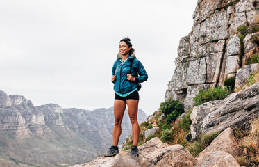 young female hiker with backpack standing on mountain enjoying the view