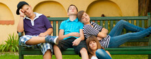 Bored Teenagers Sitting On The Bench In The Backyard On A Summer Day