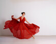 © svetograph - Dancer in a red flying dress. Woman ballerina dancing on a white studio background