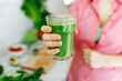 © Алина Битта - Green smoothie - healthy eating concept. faceless woman holding smoothie shake against kitchen home interior, focus on hands and glass