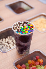 Frozen açaí in plastic cup topped with colorful candy balls. Copy space. Copy space.