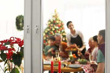 Canvas Print - Happy family enjoying festive dinner at home, view from outside. Christmas celebration