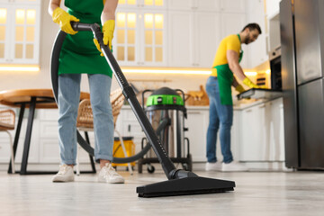 Wall Mural - Professional janitor vacuuming floor in kitchen, closeup