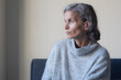© Natalie Board - Close up of seated middle aged woman in grey sweater looking annoyed (selective focus)