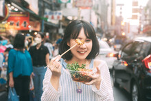 Young Adult Asian Woman Eating Food Of Spicy Grilled Squid At Southeast Asia Chinatown Market