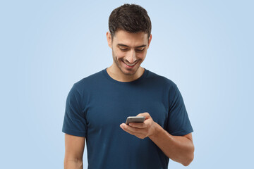 Wall Mural - Naturally laughing attractive young man looking at smartphone, smiling openly while holding it