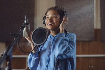 Wall Mural - Female singer records new song. Emotional actress voices text, rehearses with enjoyment and emotions in soundproof room