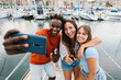 © Xavier Lorenzo - Happy young friends talking selfie with cellphone while drinking beer on a boat in summer vacation