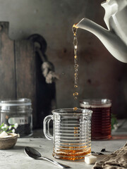 Still life with black tea poured into glass. with steam. Process brewing tea. Selective focus