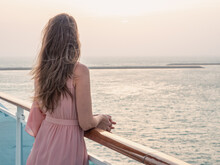 Beautiful Woman Standing On The Empty Deck Of A Cruise Liner Against The Backdrop Of The Setting Sun. Closeup, Outdoor. Vacation And Travel Concept