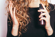 © progressman - Young woman with curly hair applying spray serum